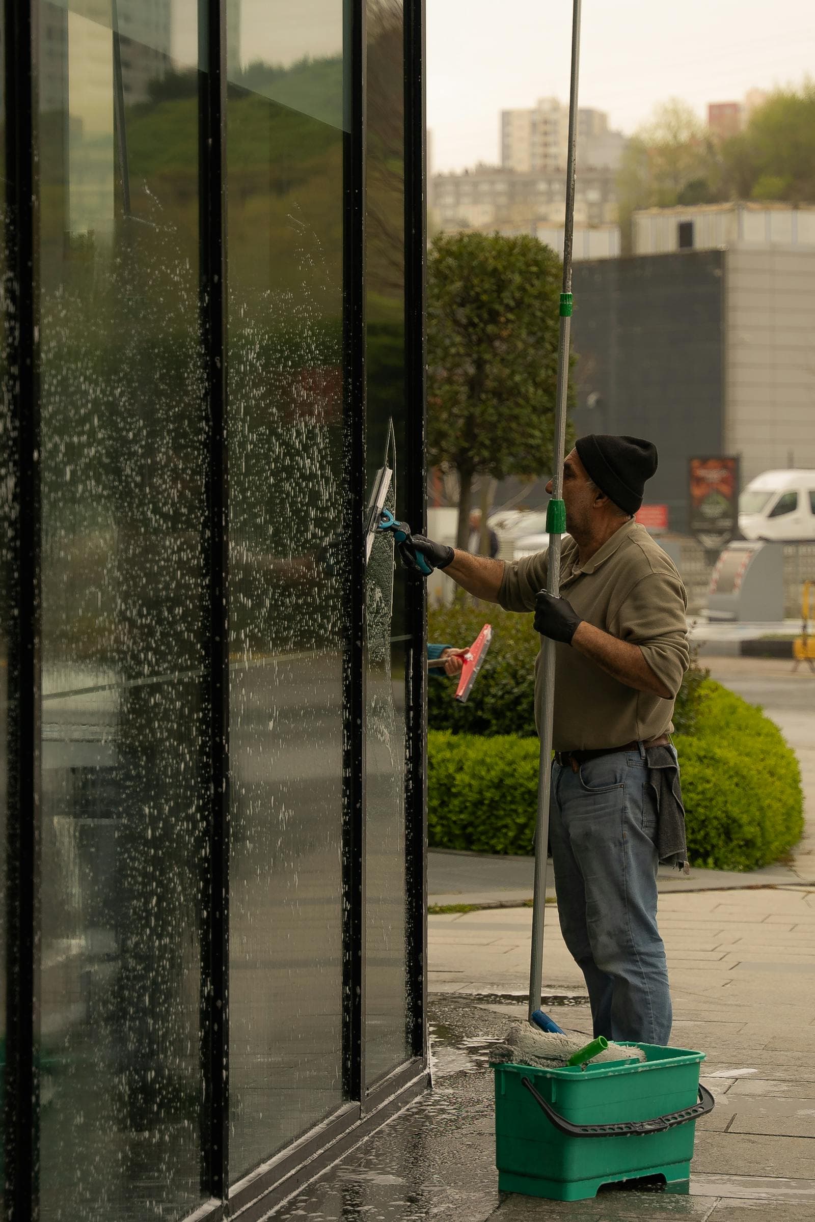 Professional window cleaner using a long-reach pole system on a building exterior