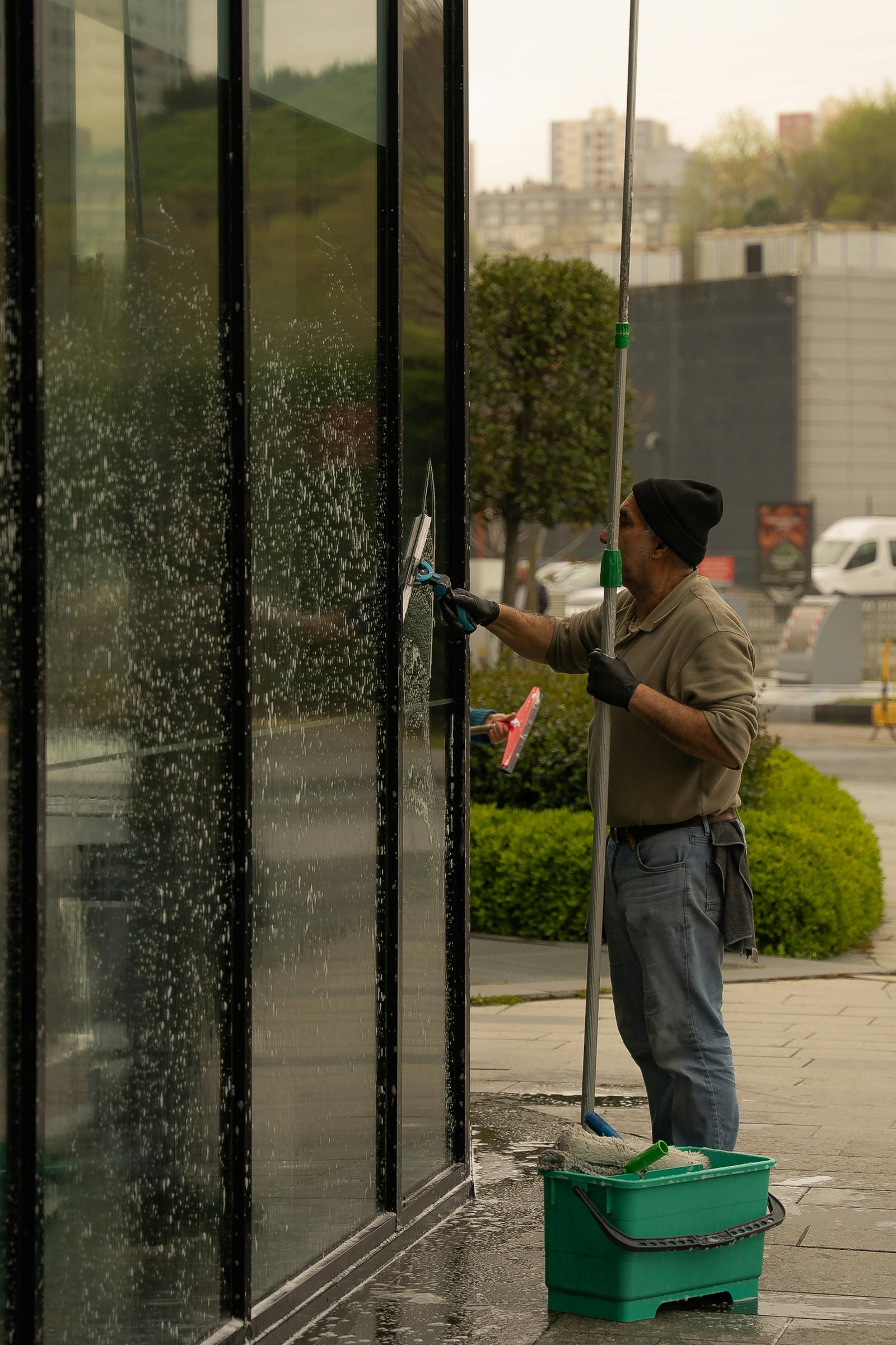 Professional window cleaner using a long-reach pole system on a building exterior